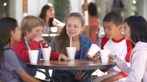 Group of teenage children sitting at table in outdoor caf\x8E and talking.Shot on Sony FS700 at frame rate of 25fps