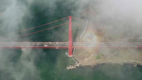 High drone flight above the clouds over the Golden Gate Bridge stretching across the strait. Mystic view of the bridge covered with clouds and panorama of the coast. United States. Time lapse, 4k.