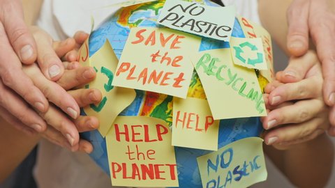 Family hands hug Earth globe with stickers with the message Save the Planet, Help and No Plastic.