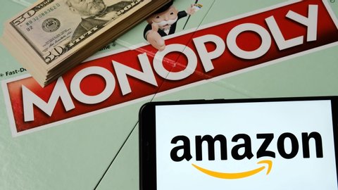 Stone, Staffordshire / United Kingdom - December 20 2019: Amazon logo on the smartphone placed next to Monopoly game where the dice rolled with double six. Conceptual video.
