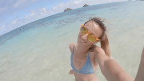 Young woman on Hawaiian beach taking cool selfies during summer vacation 