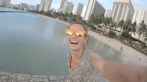 Young woman solo traveller taking selfies on famous Waikiki beach in Honolulu, Hawaii. Woman selfie time 