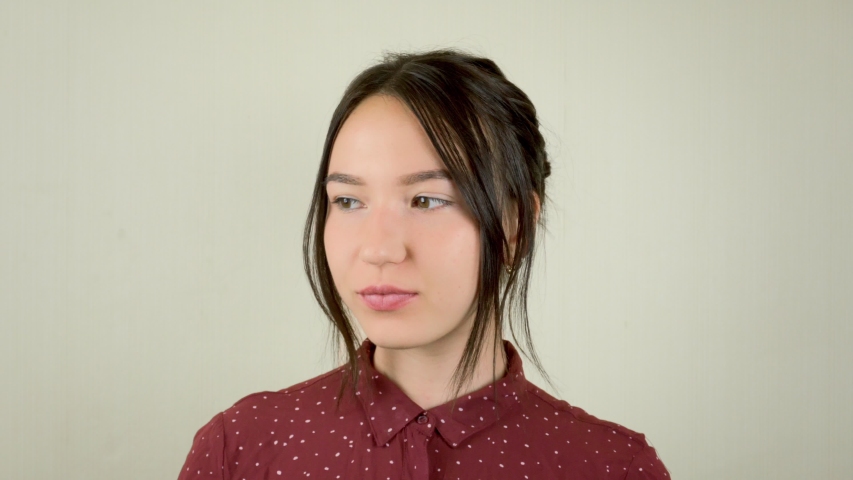 A young woman in a red shirt is looking at the camera.