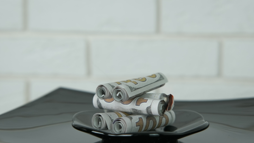 Burning business at home. A pyramid from burning dollars on the blac plate.