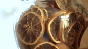 Closeup view of dry slices of oranges or lemons in glass jar. Christmas seasonal decor. Real time 4k video footage