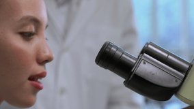 Zoom in side view video of Medical Research Scientist Looking under the Microscope in the Laboratory. 
