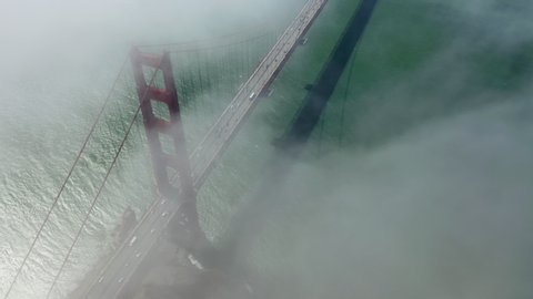 Top down aerial view over the beautiful and famous Golden Gate Bridge totally hidden with the cloud. The cloud passes by and the view of the bridge appear below. San Francisco, California. 4K