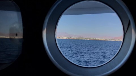 View from the window of a cruise ship porthole showing the mountains of Egypt at sunset, inside the cabin on the Red Sea cruise