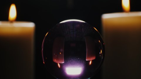 Spinning crystal ball and candle light of fortune teller or witch, concept of the magical mystery. Fortune teller table with crystal ball and candles