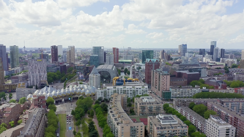 Rotterdam, Netherlands. Panoramic cityscape with futuristic Markthal and geometric Cube Houses under a dramatic cloudy sky. Aerial view