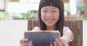 little girl watch video by mobile happily when go traveling - location okinawa and japan
