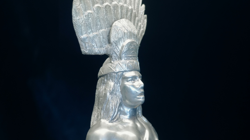 Figurine of the North American Indian from white metal rotates on a black background. Macro. Closeup