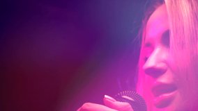 Singing Woman with Microphone. Karaoke bar. Beauty Glamour Singer Girl close-up. Stage. Rock star singer on music concert over colorful lights background. Song. Pop music. Slow motion 4K UHD
