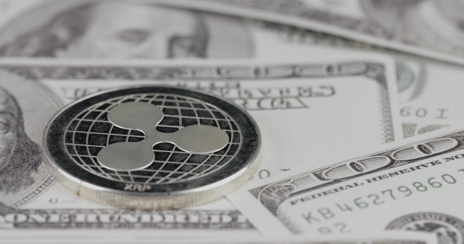 4k resolution of a cryptocurrency silver Ripple coin on a hundred usd dollars bills. Close-up, macro shot - slider movement