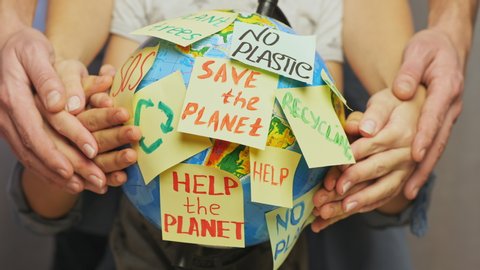 Family hands hug Earth globe with stickers with the message Save the Planet, Help and No Plastic, Recycling, SOS. Concept save our planet