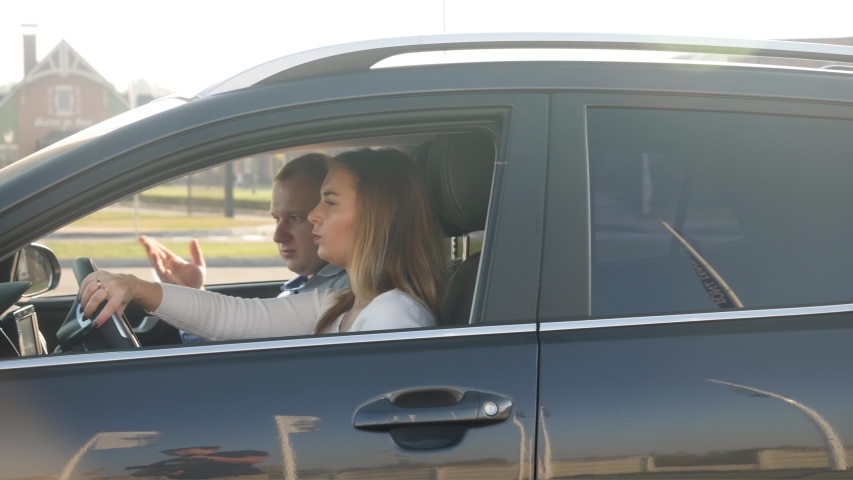 4k footage of male driving instructor sitting on passenger seat in car and showing way to female student in driving school Royalty-Free Stock Footage #1043301895