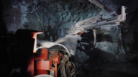 Rock surface drilling machine used to drill blast holes at mine tunnel. Mining excavator drills a hole in the rock in copper pyrite mine. A large industrial drill boring into a rock wall.