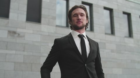 Portrait of a young fair-haired bearded man showing middle finger gesturing fuck. White man makes fuck gesture with a hand on business building background.