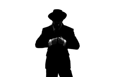 Silhouette Elegant man in a black hat is dancing an erotic dance. He uses a chair and a cigarette. White background. Close up, slow motion.