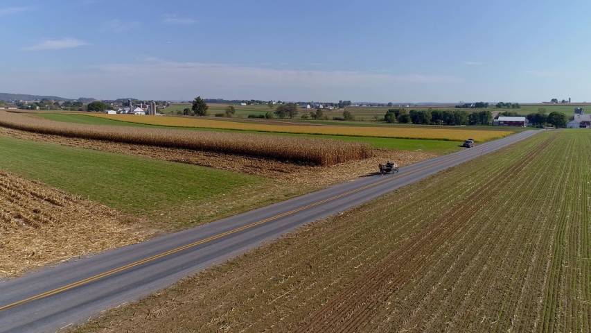 Drone Flight over Agricultural Fields and a Approaching Amish Horse and Buggy with Blue Skies

