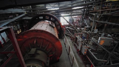 Big ball mill grinds ore on the ore-dressing factory. Industrial grinder at manufacture rotating. Copper processing industry.