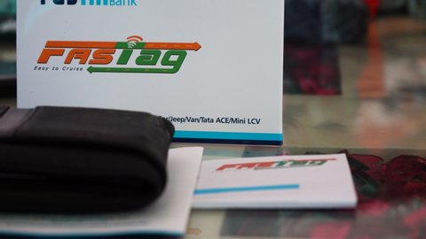 Delhi, India - circa 2019 : Panning shot of a new FASTag RFID sticker with the envelope, a wallet for payment and some cash. The national authority of India has made these mandatory to ensure cashless