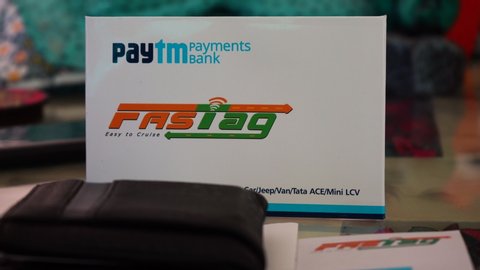 Delhi, India - circa 2019 : Panning shot of a new FASTag RFID sticker with the envelope, a wallet for payment and some cash. The national authority of India has made these mandatory to ensure cashless