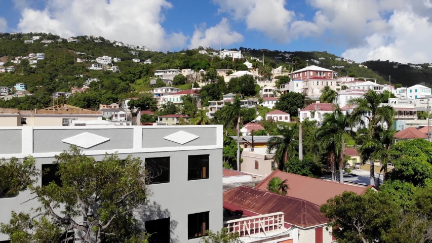 Drone is slowly rising from the main street to reveal beautiful residential houses on the hill in Charlotte Amalie, St Thomas, USVI. Tilt shot.