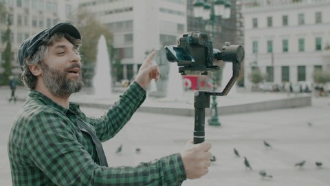 Social media influencer filming himself talking to camera in urban environment.Making of of a shoot where an adult male is using camera gear to film his social media show or video in a European city.

