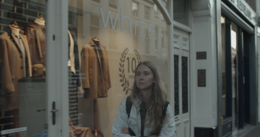 Young atractive woman blonde wearing jeans jacket walking in the streets of Den Haag with her backpack