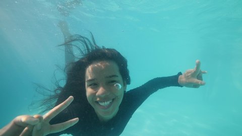 Young attractive funny girl with child smiling and shouting diving underwater.