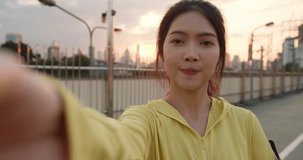 Attractive young Asia athlete influencer lady recording video vlog live streaming on phone upload in social media while exercises in urban city. Sportwoman wearing sports clothes on street in morning.