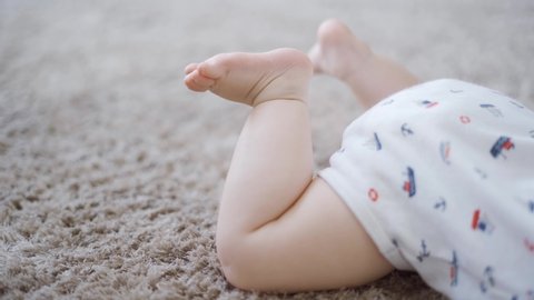 Baby feet lying on the carpet in the living room at home. Shot in 4k resolution