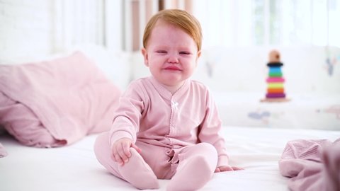 upset little baby girl crying and laughing on the bed