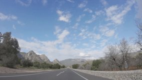 4K POV footage of car driving on highway road . Blue sky and beautiful mountain landscape on horizon. Flowering almond gardens and citrus trees on the sides. Spring on Mallorca island. Slow motio
