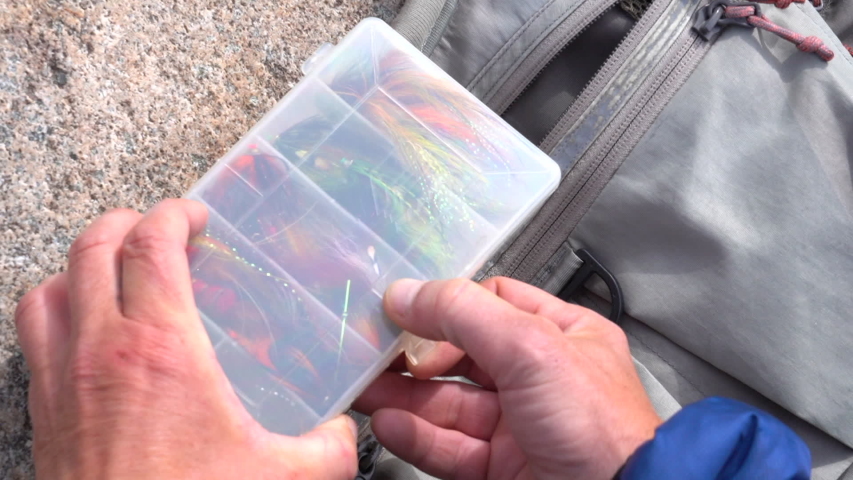 fisherman holds flybox and picks salmon flies