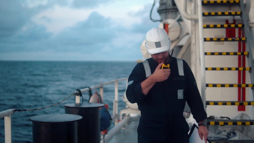 Marine Deck Officer or Chief mate on deck of vessel or ship . He holds VHF walkie-talkie radio in hands. Ship communication Royalty-Free Stock Footage #1043392594