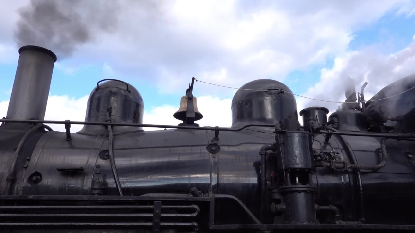 Top of black old antique steam locomotive engine with black smoke coming from smokestack  