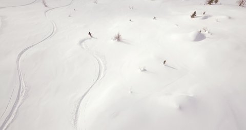 Aerial follow camera of a male freeride skier that is doing powder turns down a mountain in Salzburg Austria Gastein