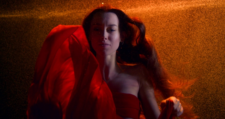 sensual brunette girl is floating inside dark water of swimming pool