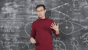 Medium shot of handsome young scientist presenting his report while standing against blackboard with formulas written on it - Powered by Shutterstock - Get 15% off with code: PIKWIZARD15