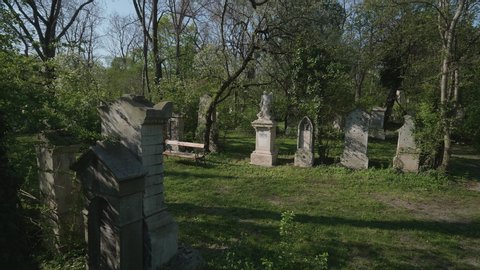 VIENNA AUSTRIA April 18. 2019 - BIEDERMEIER CEMETERY SANKT MARX - segway dolly shot going along old grave stones between trees and bushes on St.Marx cemetery where Wolfgang Amadeus Mozart is buried
