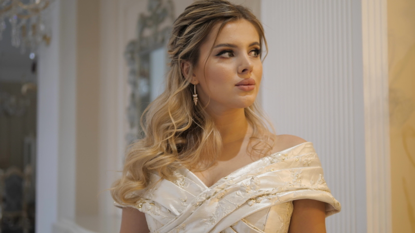 thoughtful blonde lady with juicy lips poses looking away at photoshoot in castle room slow motion close view