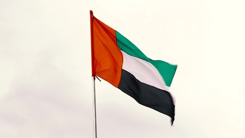 Flag of United Arab Emirates against cloudy white sky in a winter day UAE flag waving in Dubai city , national symbol of UAE. blue sky, uae flag perfect for film, news, digital composition.
