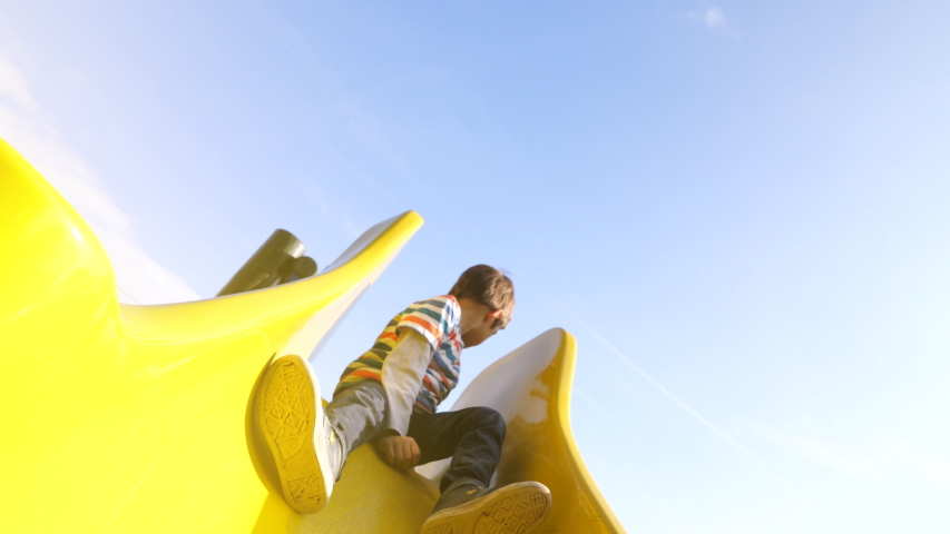 A kid going down a yellow slide in slow motion Royalty-Free Stock Footage #1043408299