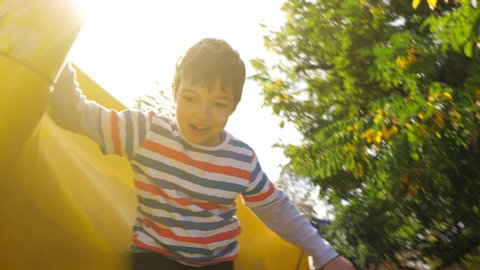 A kid going down a yellow slide in slow motion