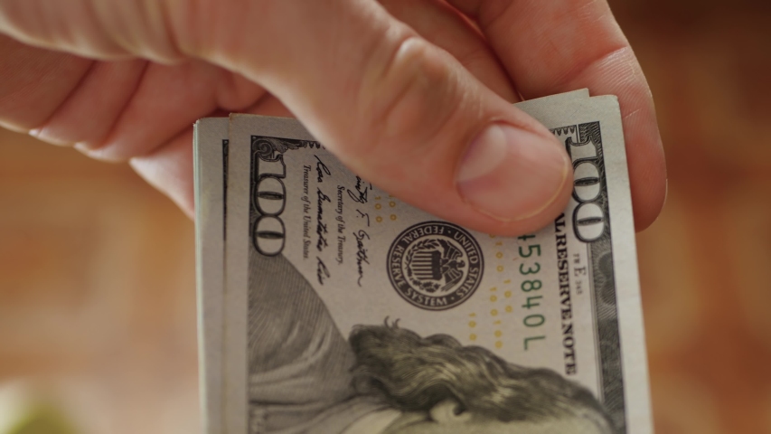 One hundred dollar bills close up. A man counts his money. Currency exchange and movement. Business and finance.