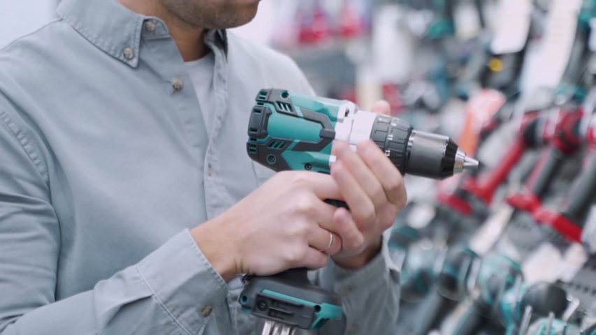 A young man chooses cordless screwdriver in the hardware store Royalty-Free Stock Footage #1043414287