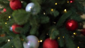 Closeup view of beautiful decorated green Christmas tree. Blurry holiday video background. Real time 4k video footage.
