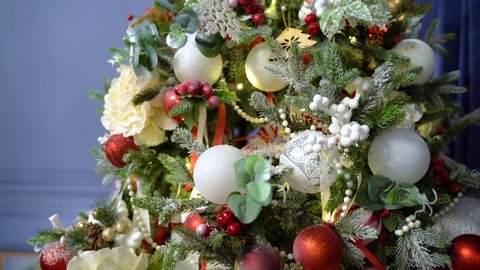 White balls and illuminated garland with flashlights. Gimbal tilt up shot of artificial christmas green tree